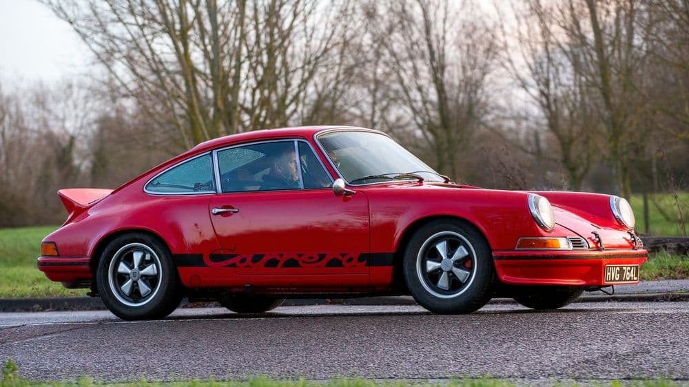 Red Porsche 911 Carrera RS 2.7 with its ducktail spoiler and Carrera script, the template for the air-cooled 911 investment tier.
