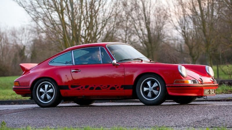 Red Porsche 911 Carrera RS 2.7 with its ducktail spoiler and Carrera script, the template for the air-cooled 911 investment tier.